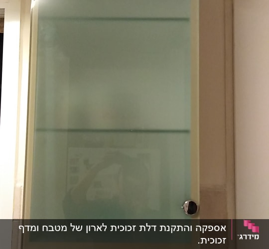דלת זכוכית חלבית עם ידיות מתכת בארון מטבח